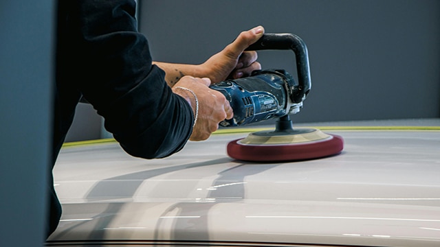 Someone holding a buffing while on top of car