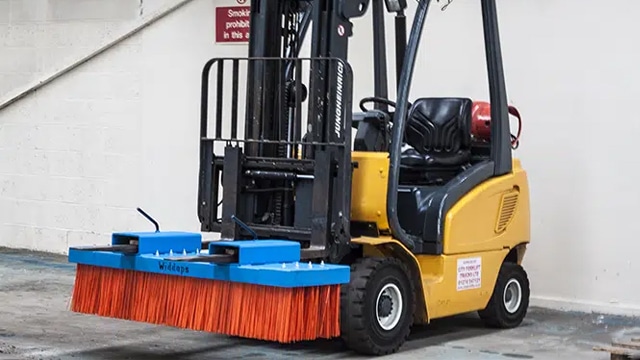 Yellow forklift truck with blue and orange forklift sweeper attachment